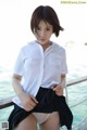 A woman in a white shirt and black skirt posing on a boat.