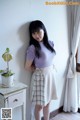 A woman standing in front of a window wearing a skirt.
