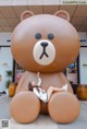 A woman laying on top of a giant brown teddy bear.