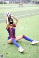 A woman sitting on the ground holding a soccer ball.