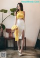 A woman in a yellow top and white skirt posing for a picture.