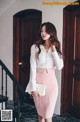 A woman in a white shirt and pink skirt posing for a picture.