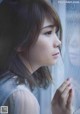 A woman looking out of a window with her hand on the window sill.