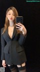 A woman in a black suit taking a selfie.