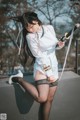 A woman in a white shirt and black stockings holding a sword.