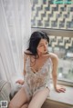 A woman in a white lingerie sitting on a window sill.