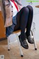 A woman sitting on a chair wearing black tights and a red tie.