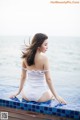 A woman in a white bathing suit sitting on the edge of a pool.