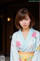 A woman in a blue kimono standing in front of a door.