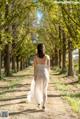 A woman in a white dress walking down a dirt road.