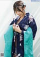 A woman in a blue and green kimono is posing for a picture.