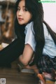 A woman with long black hair sitting on the floor.