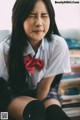 A woman in a school uniform sitting on a bench.