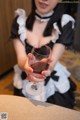 A woman in a maid outfit holding a glass of wine.