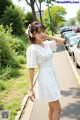 A woman in a white dress standing on a sidewalk.