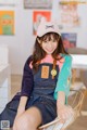 A woman sitting on a chair wearing a cat hat.