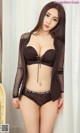 A woman in a black bra and panties posing for a picture.