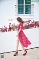 A woman in a red dress is walking down the street.