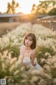 A woman in a white dress sitting in a field of tall grass.