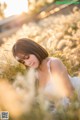 A woman in a white dress laying in a field of tall grass.