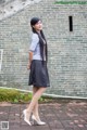 A woman standing in front of a brick wall.