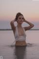 A woman in a white bikini standing in the water.