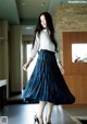 A woman in a white shirt and blue pleated skirt.